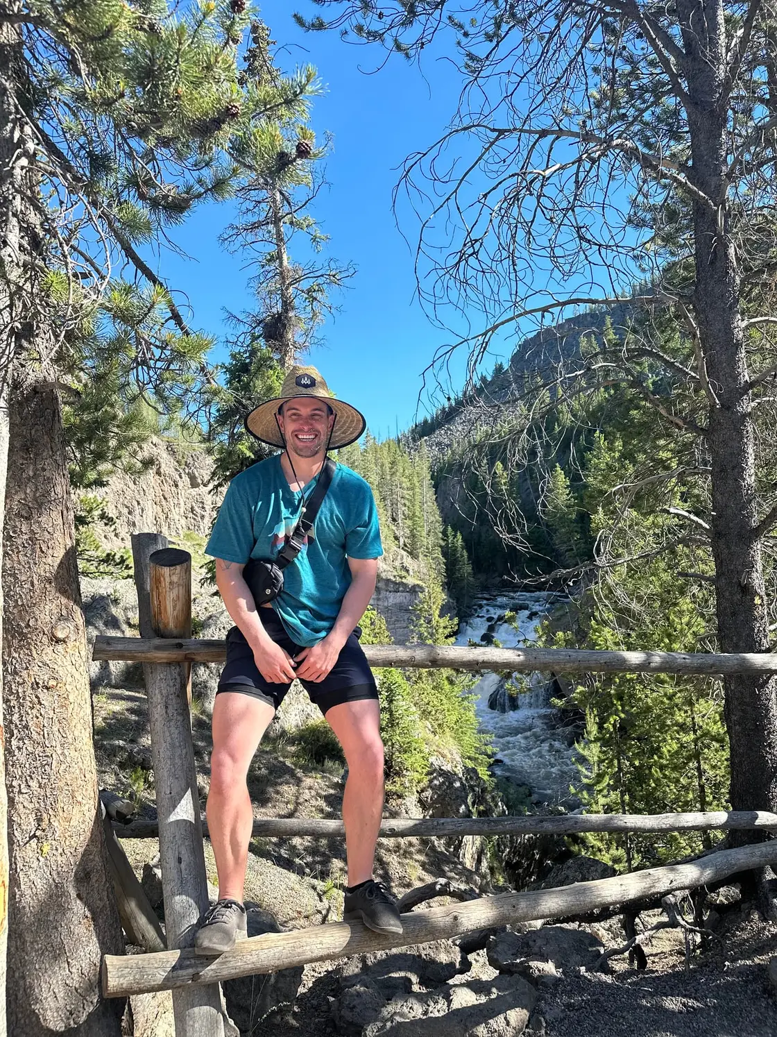 Zack sitting on a wooden fence above the Firehole River in Yellowstone